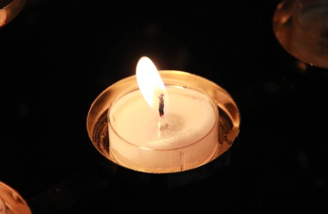 Single tealight candle burning in the dark