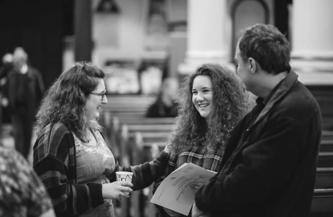 Three young people smiling and chatting inside church 