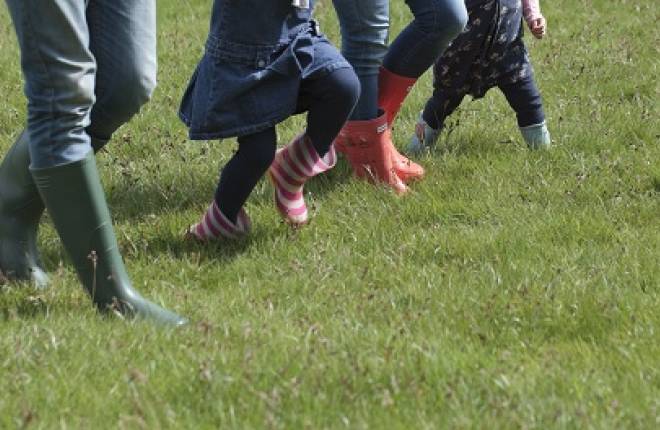 Feet in wellies walking across a field of grass