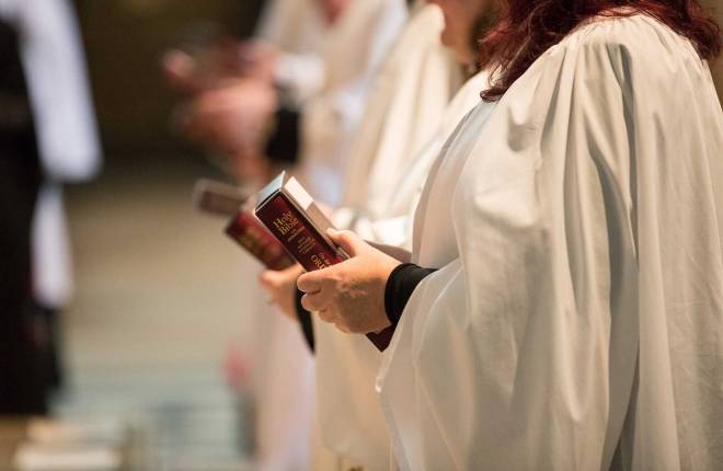 Female clergy holding bible at ordination service