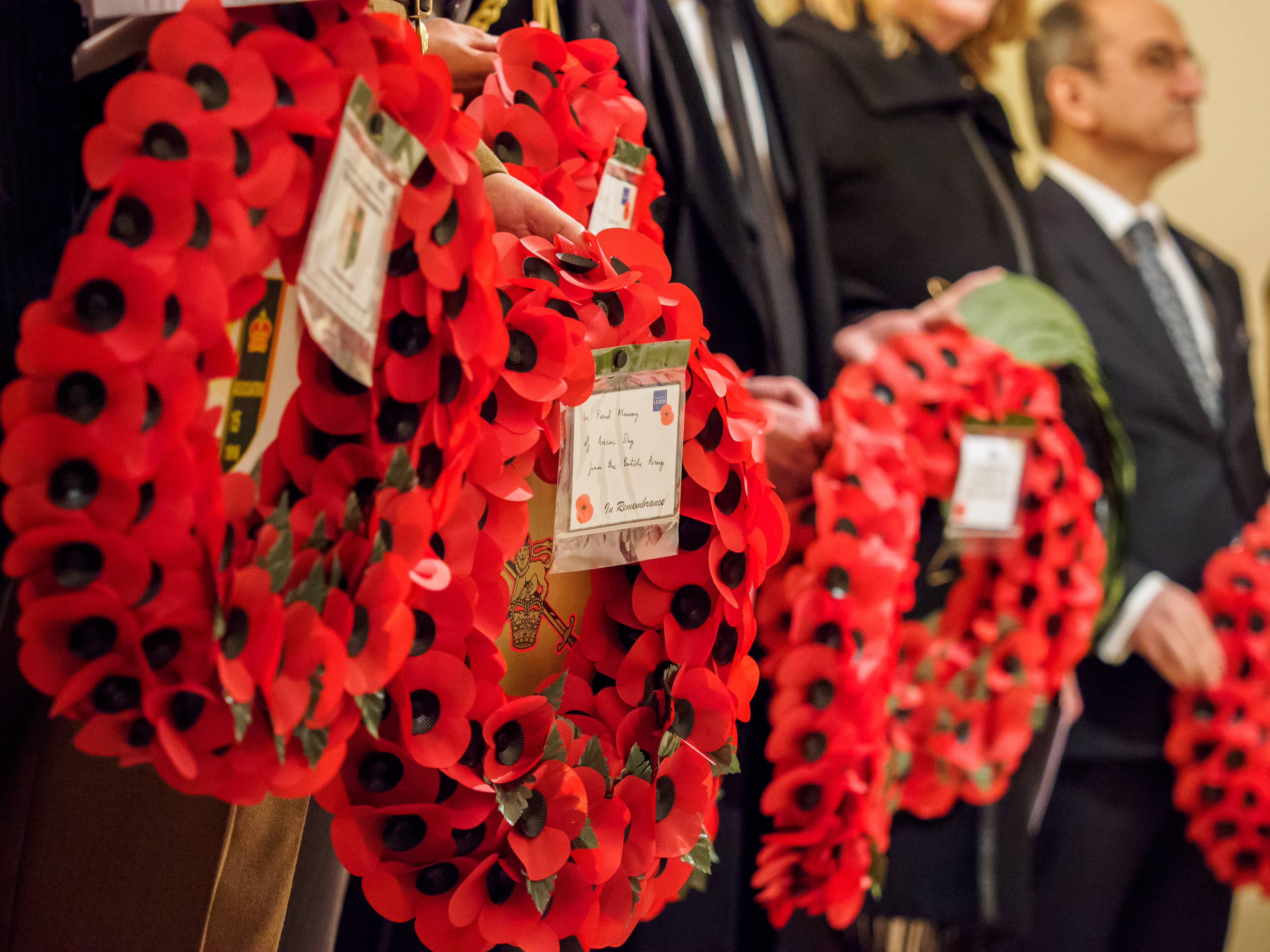 People in a row holding wreaths made from poppies 