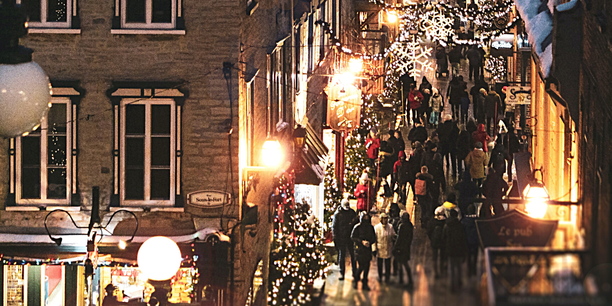 A photograph  of a street at Christmas time with people and christmas lights