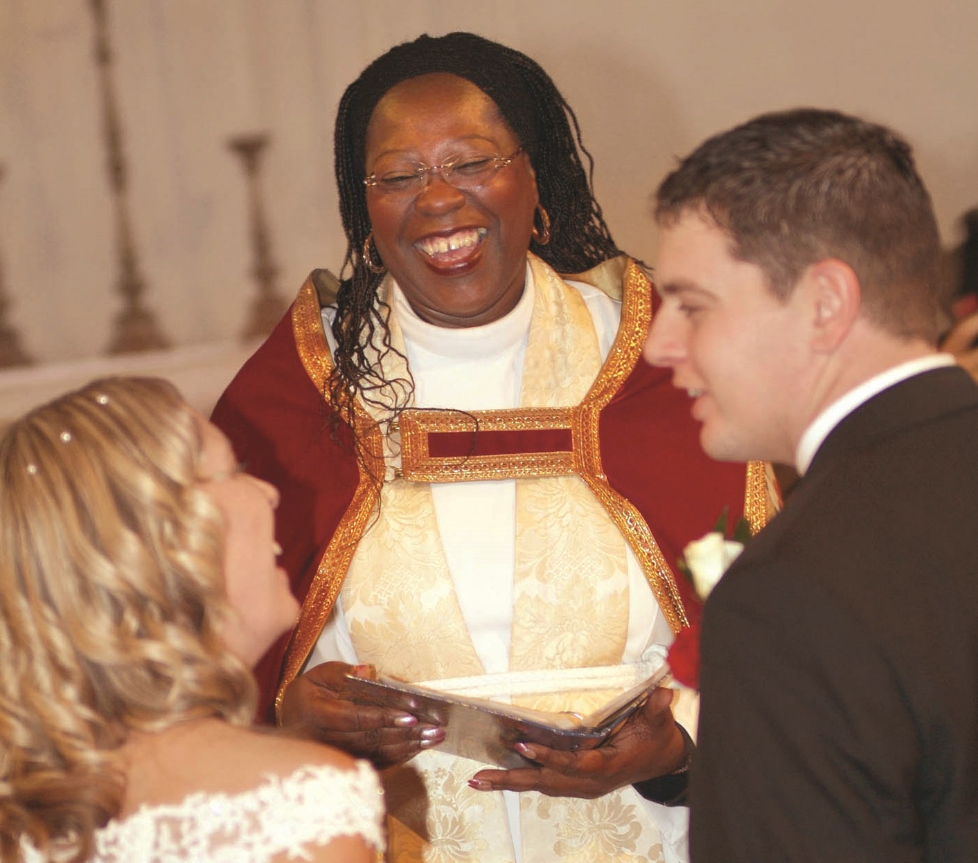 A vicar laughing with a wedding couple
