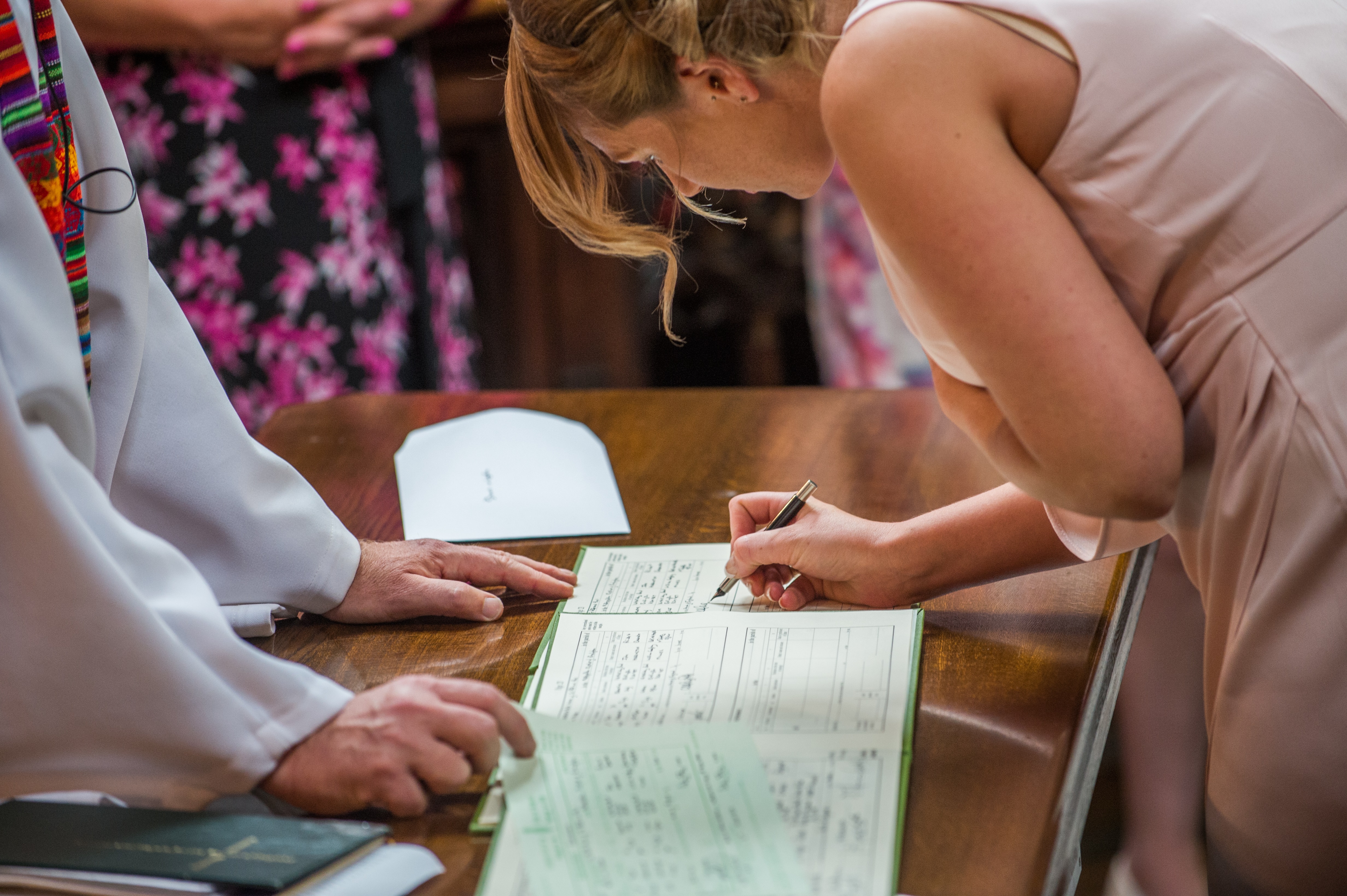 A bridesmaid signing the official paperwork at a wedding