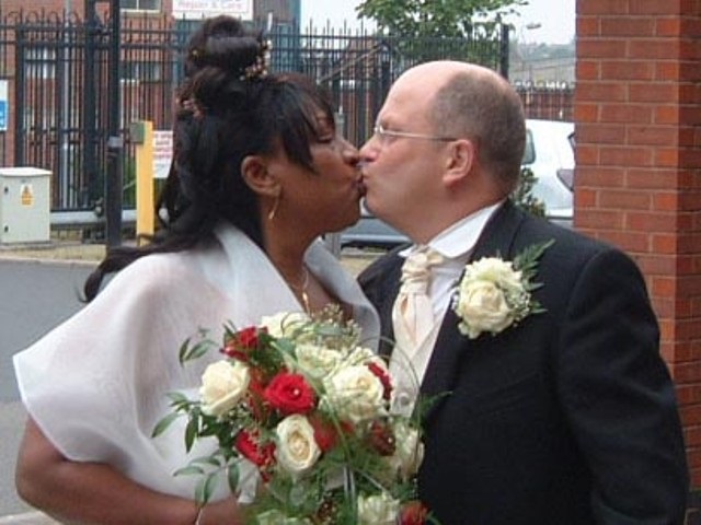 A wedding couple kissing outside the football ground