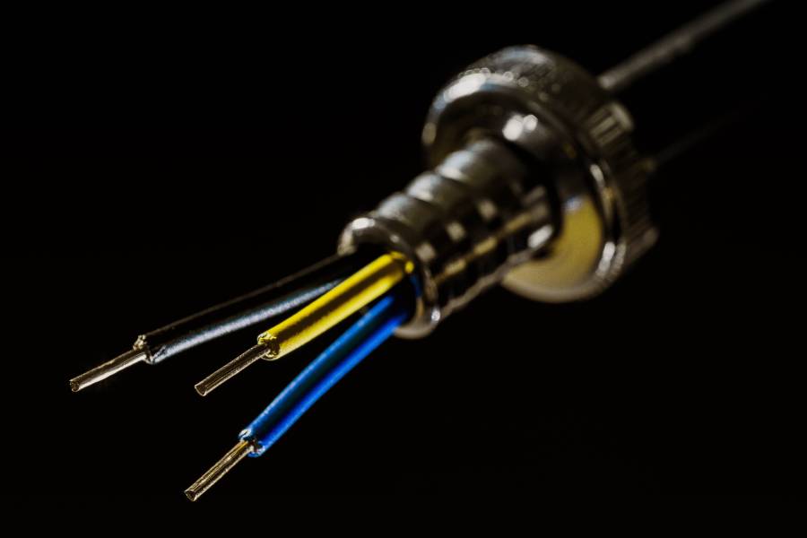 Close up of the ends of a black, yellow and blue electrical wire on black background