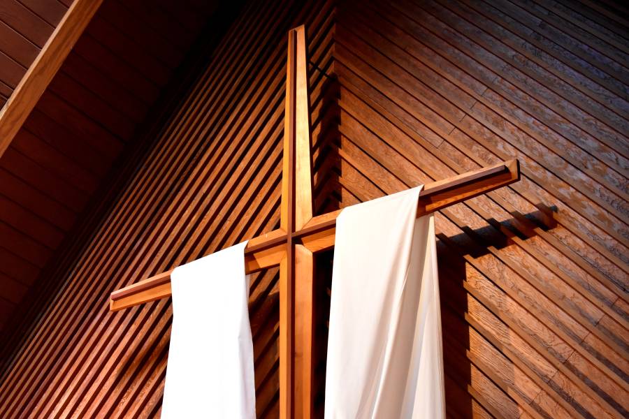 A suspended wooden cross with white cloth draped over.