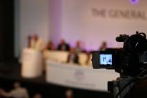 Film camera pointing at stage for General Synod 