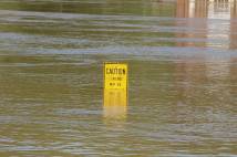 Water rising above a caution sign with a building in the background