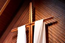A suspended wooden cross with white cloth draped over.