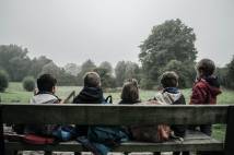 Five children sat on a bench looking out to a green park