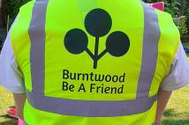 A man in a gilet with 'Burntwood be a friend' written on the back 