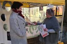 Lady handing over a leaflet to another lady in front of stall