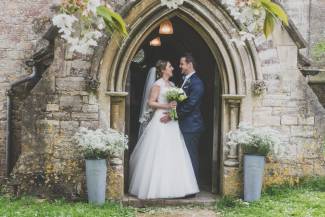 Bride and groom standing in church doorway facing each other