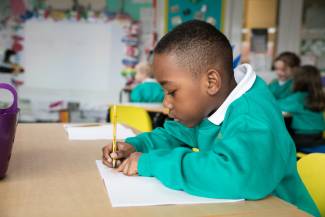 Young school child writing at table in class