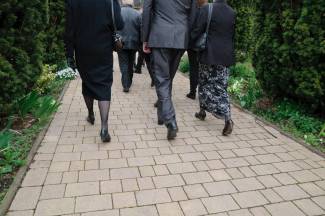 Close up of the feet of mourners walking up the path to a church
