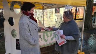 Lady handing over a leaflet to another lady in front of stall