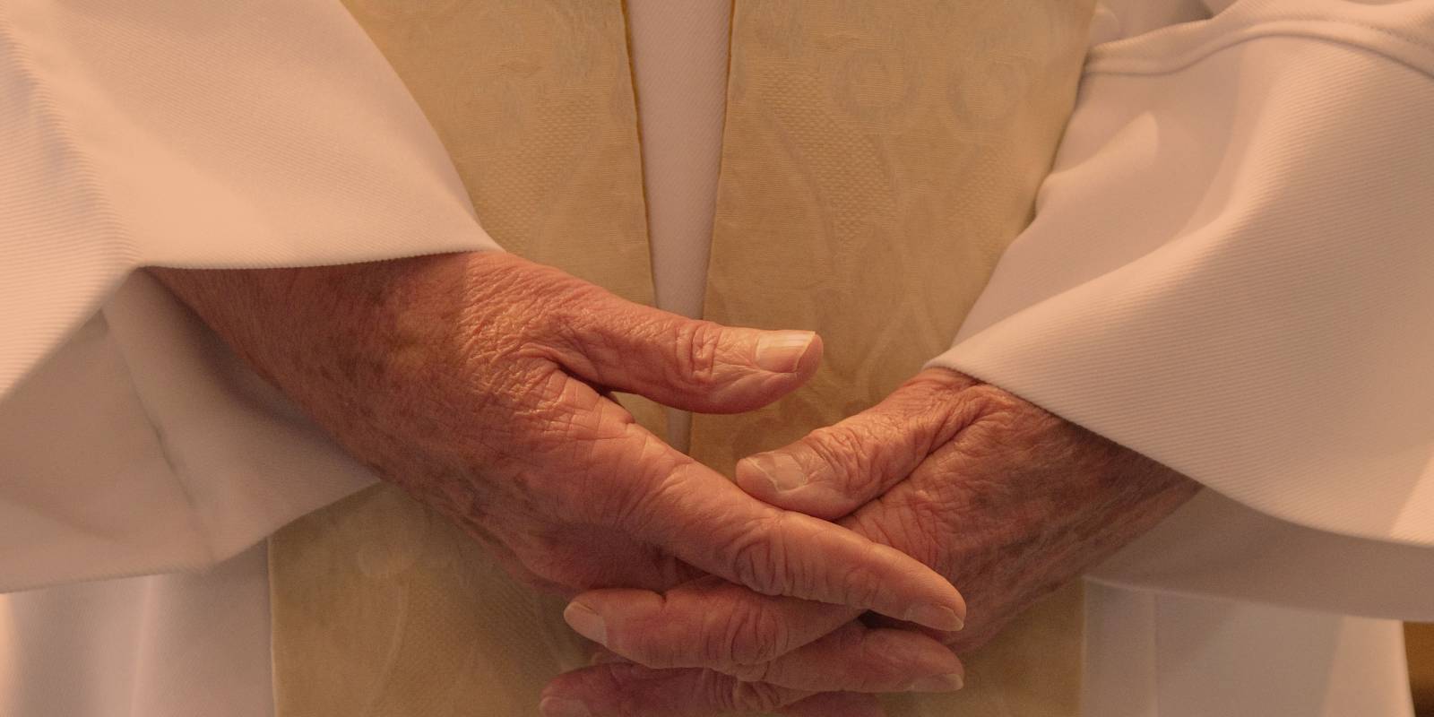 Close up of person wearing robes, hands held held together