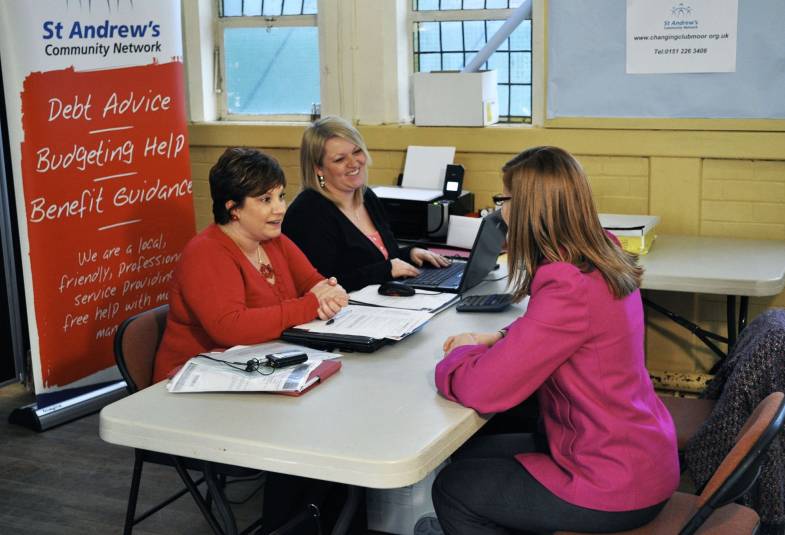 three people talking at a table, debt advice banner in the background