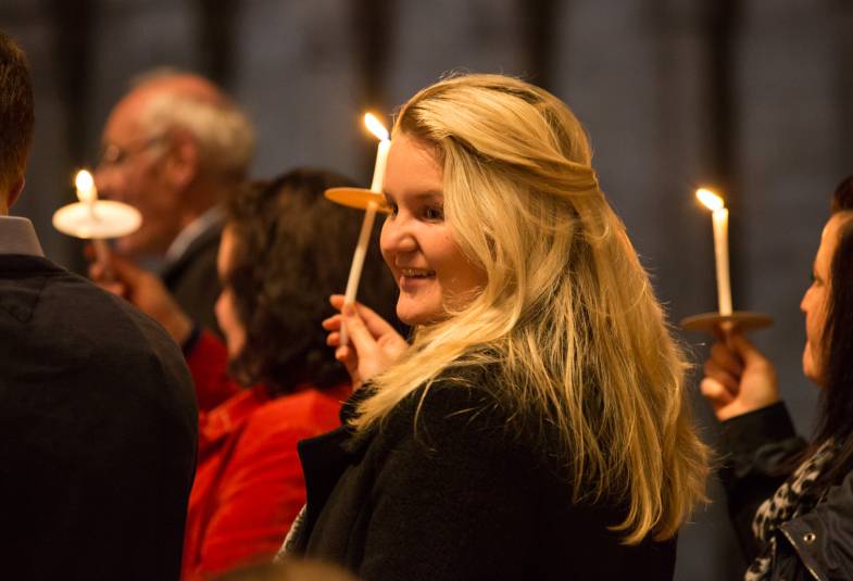 Young woman smiling, holds candle at service 
