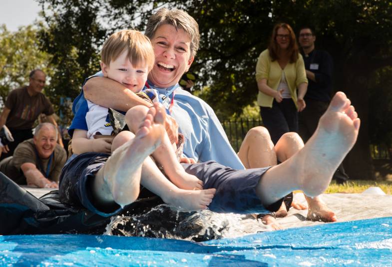 Vicar and child laughing as they go down waterslide