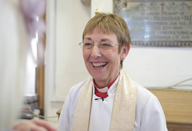 Smiling female vicar in robes