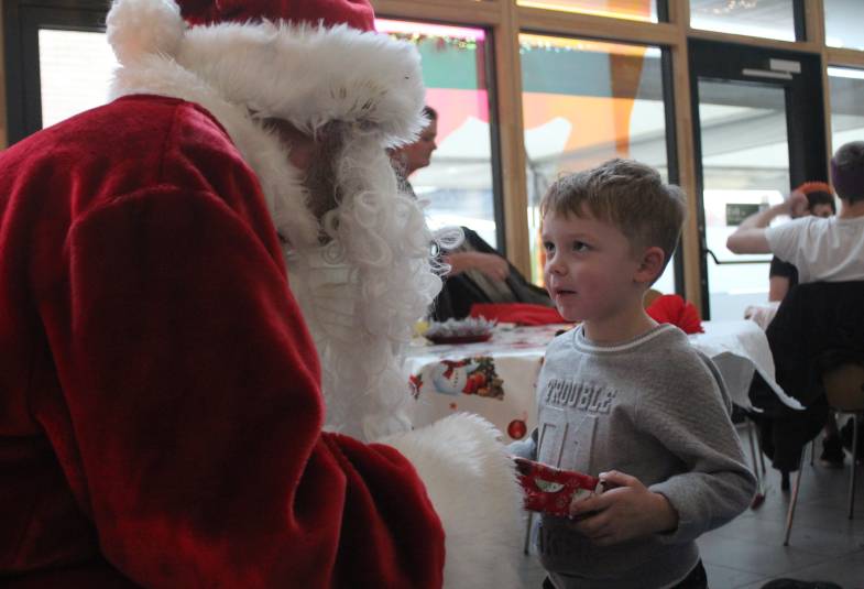 A little boy receiving a present from Father Christmas