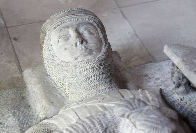 Close up of the head of a Medieval soldier's effigy made of white stone