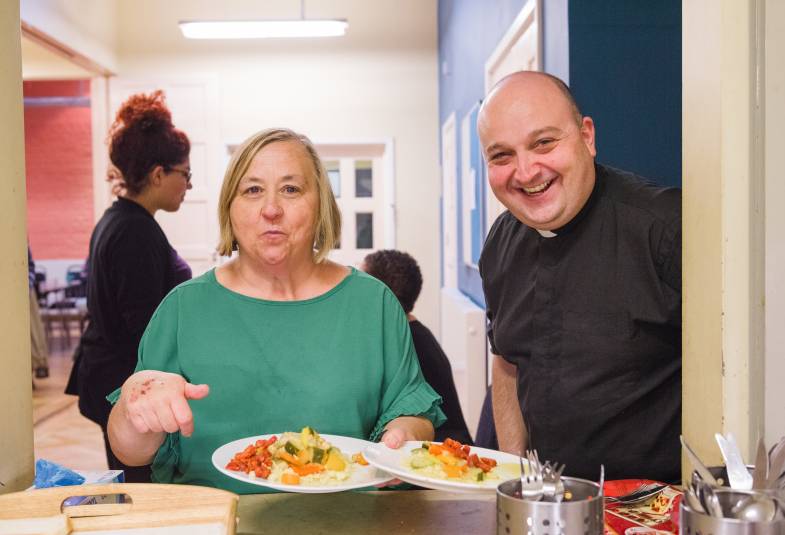 Vicar and volunteer serving food at soup kitchen