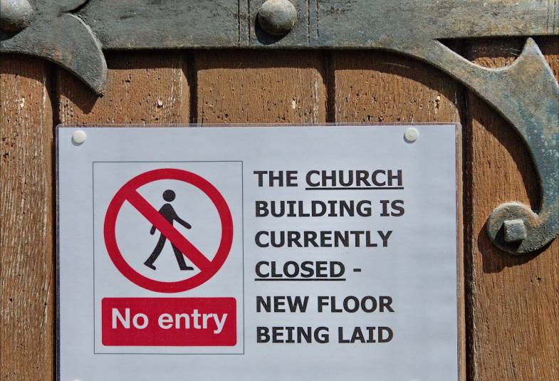 Close up of a sign on a door that says the church is closed while a new floor is being laid