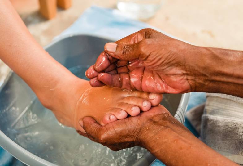 Two hands washing a persons feet
