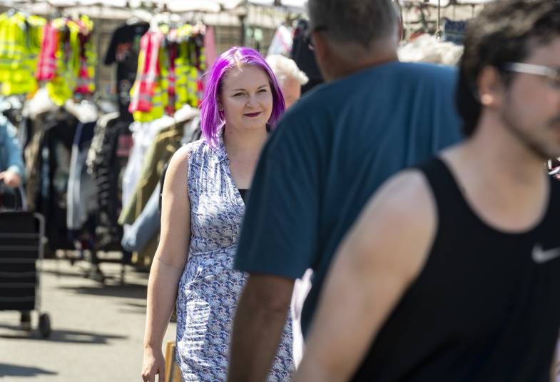 Woman with purple hair walking through a busy market