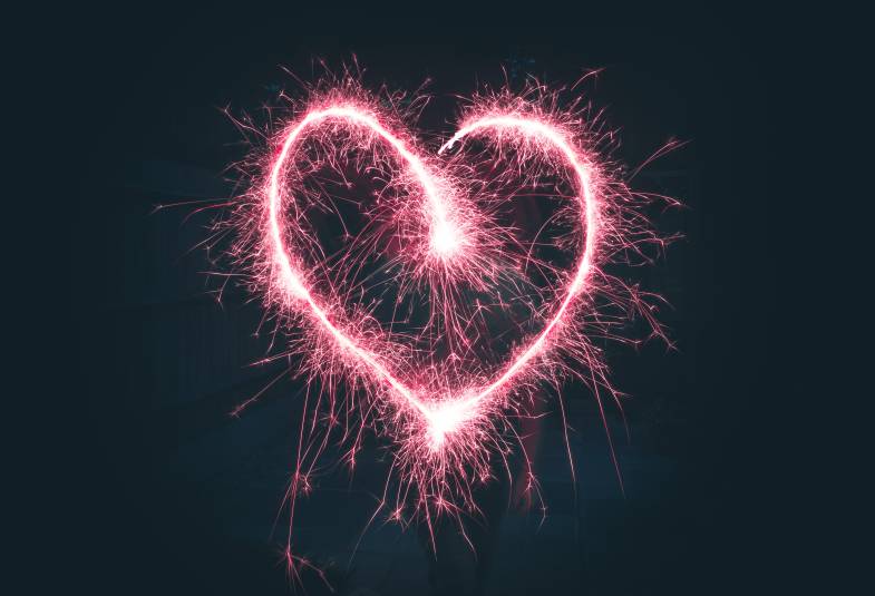 A heart traced out by sparklers in bright pink.