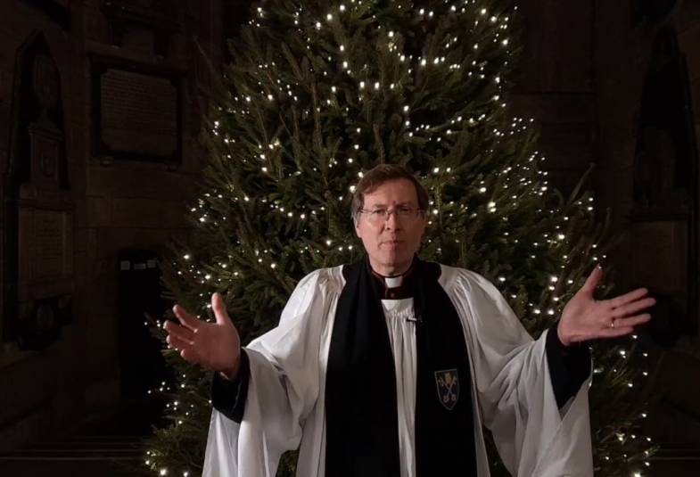 The Revd Canon Paul Maybury, Bradford Cathedral Canon Precentor, in prayer is shown with a Christmas tree behind him