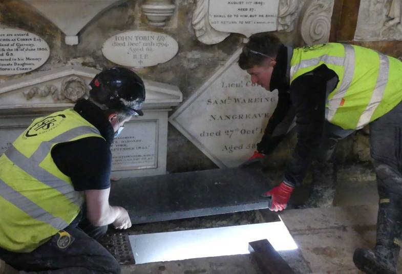 Bath Abbey workers shown in Hi-Viz clothing they're laying the final stone above the new heating system