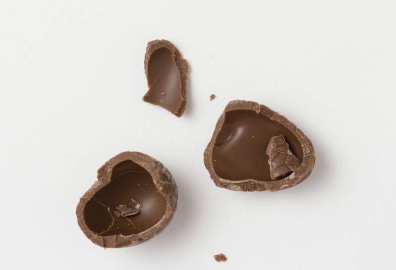 A broken up chocolate Easter egg on a white table