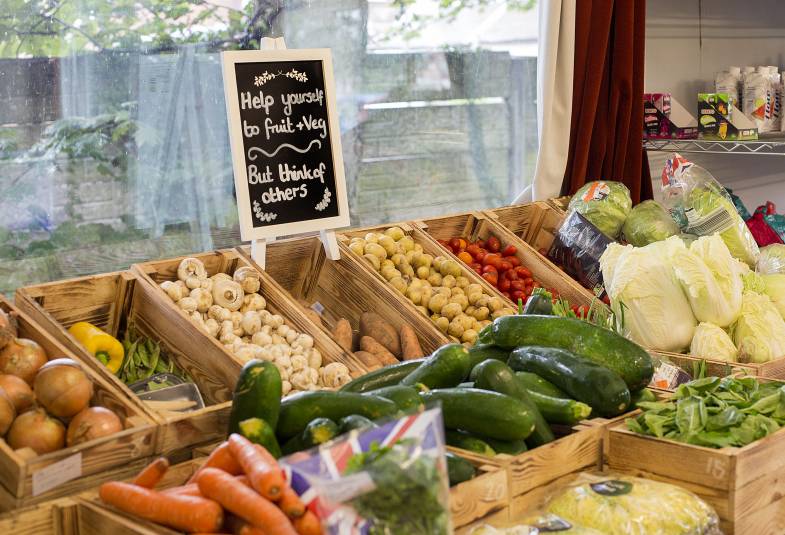 Vegetables are shown laid out with a chalk sign saying "Help yourself to fruit and vegetables but think of others"