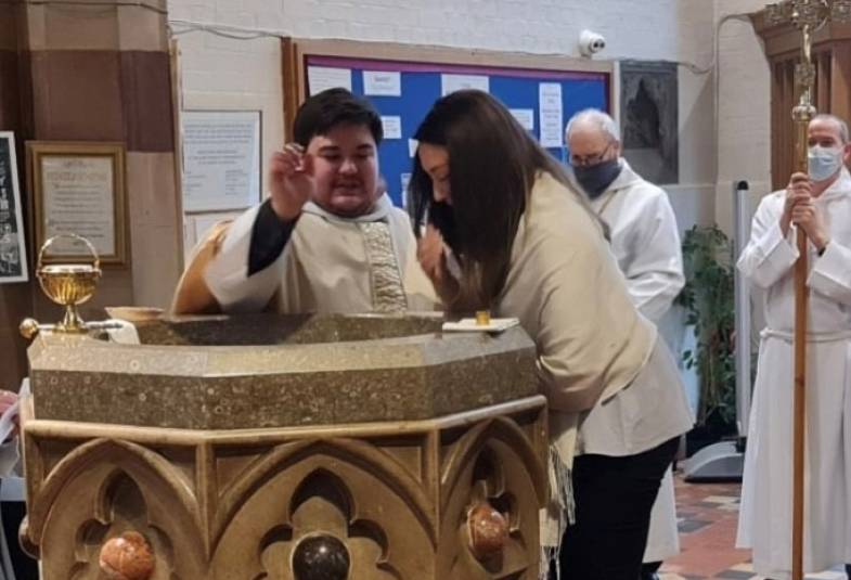 A priest baptizes a woman at a font
