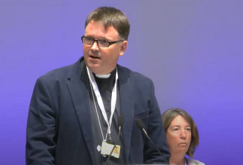Bishop Graham Usher is shown standing on the stage before Synod in York voted for the net zero carbon Routemap