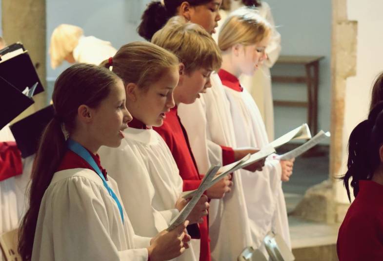 A line of choristers in robes singing from sheet music
