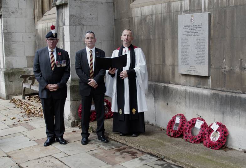 A vicar and military personnel by a war memorial