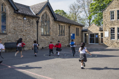 Children run towards a school building