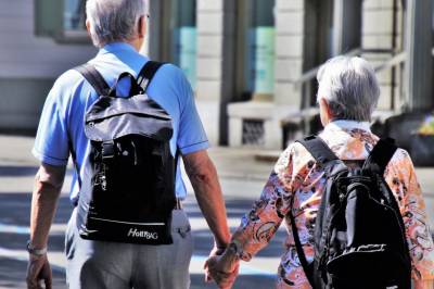 A senior couple walk hand in hand down a quiet urban street