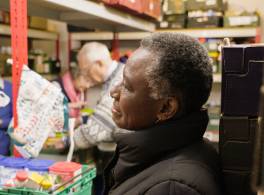 Profile of woman in a food bank, volunteers working in the background