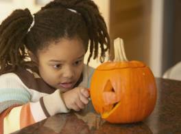 Girl carving a pumpkin on a table