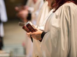 Female clergy holding bible at ordination service