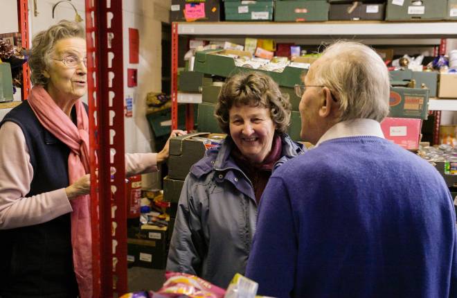 Three volunteers talking to each other inside a foodbank