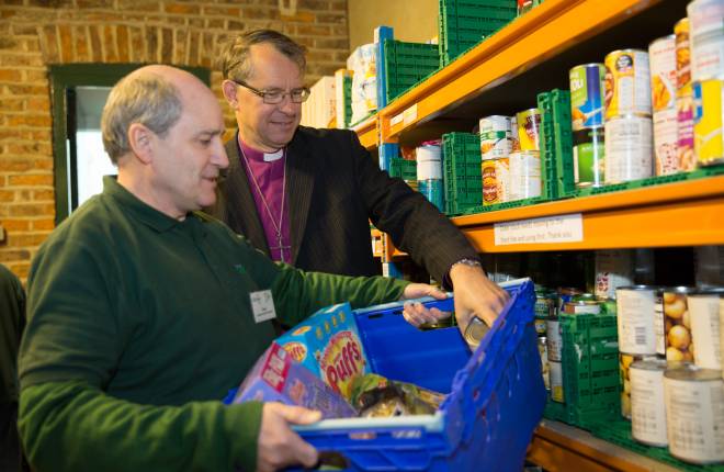 Bishop and foodbank volunteer picking food items for parcel 