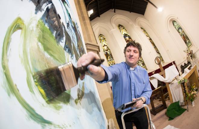 Male clergy member painting canvas inside church