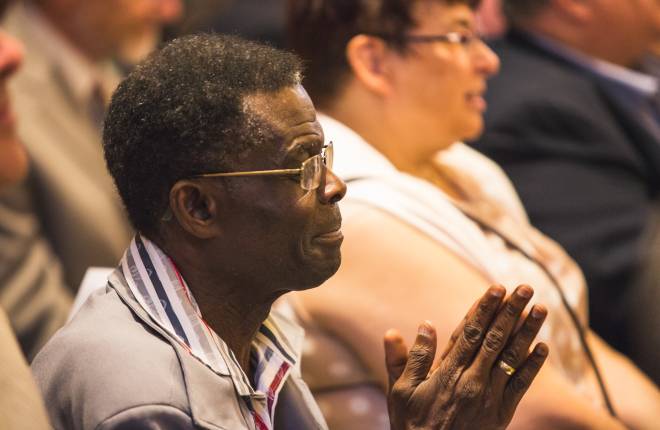 Man sitting at church service, hands together in prayer